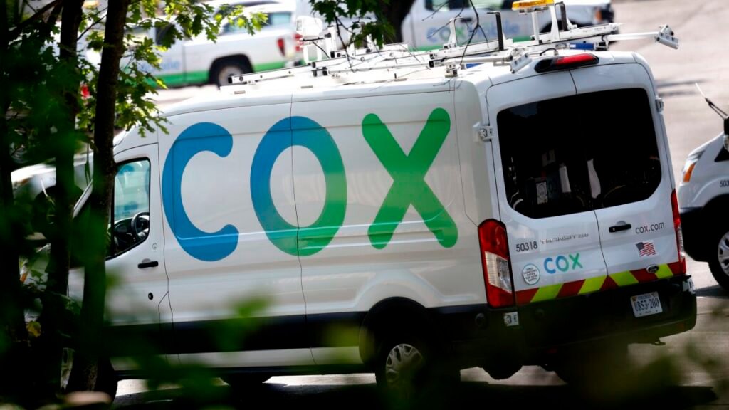 A cable service van with a large Cox logo painted on its side.