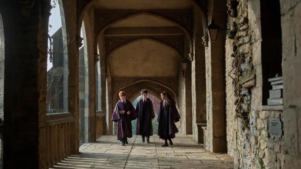 The actors playing Harry, Ron and Hermione walk in a school corridor
