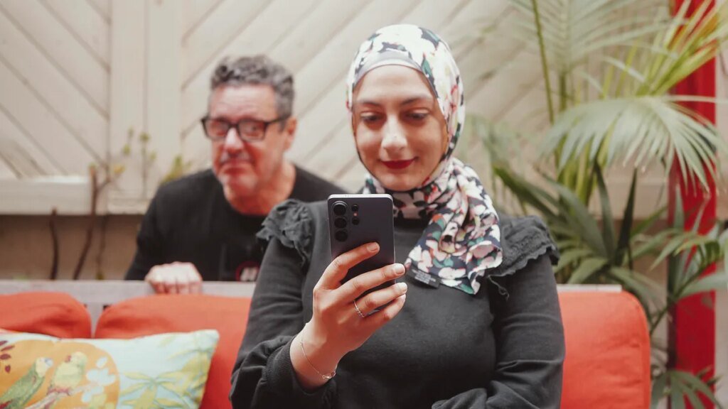 image of a creepy man looking at a phone at MWC 2026