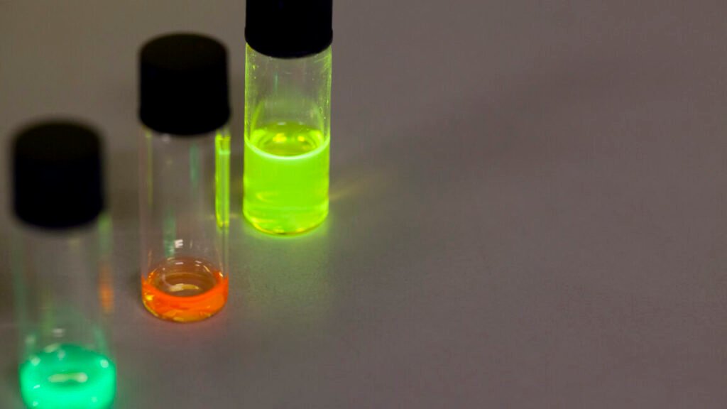 Three small jars that have (left to right) teal, red, and green-colored quantum dots
