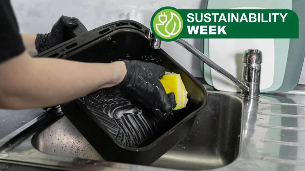 Person wearing black gloves washing air fryer basket in kitchen sink