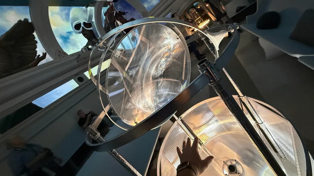 A hand reaching into a hand tracking instrument that glows while mural art hangs in the background