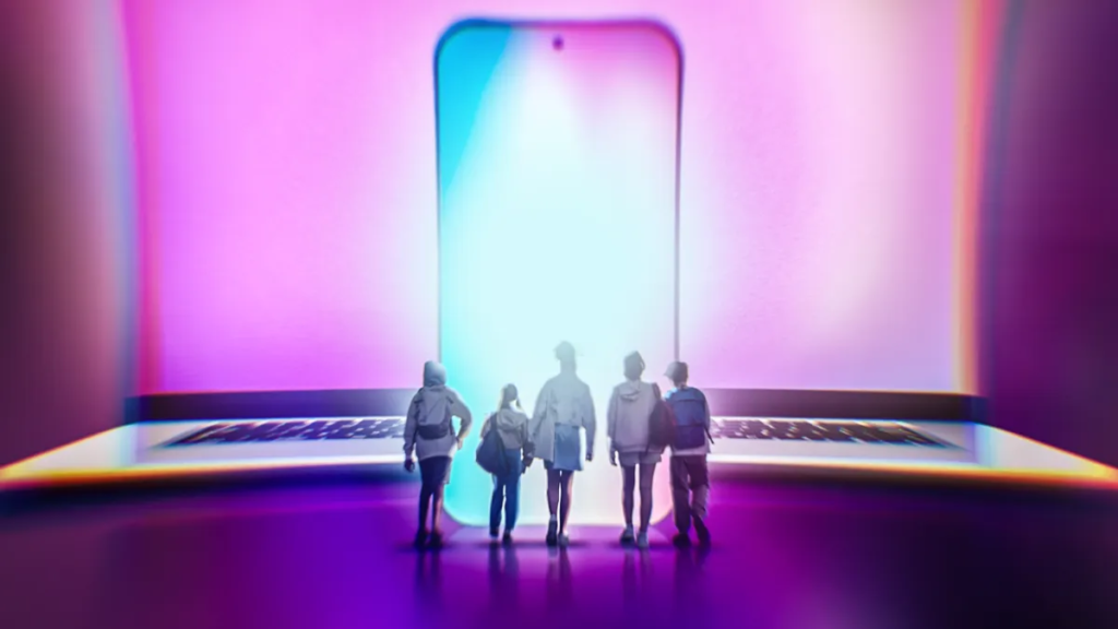A group of teens standing before a glowing smartphone and laptop