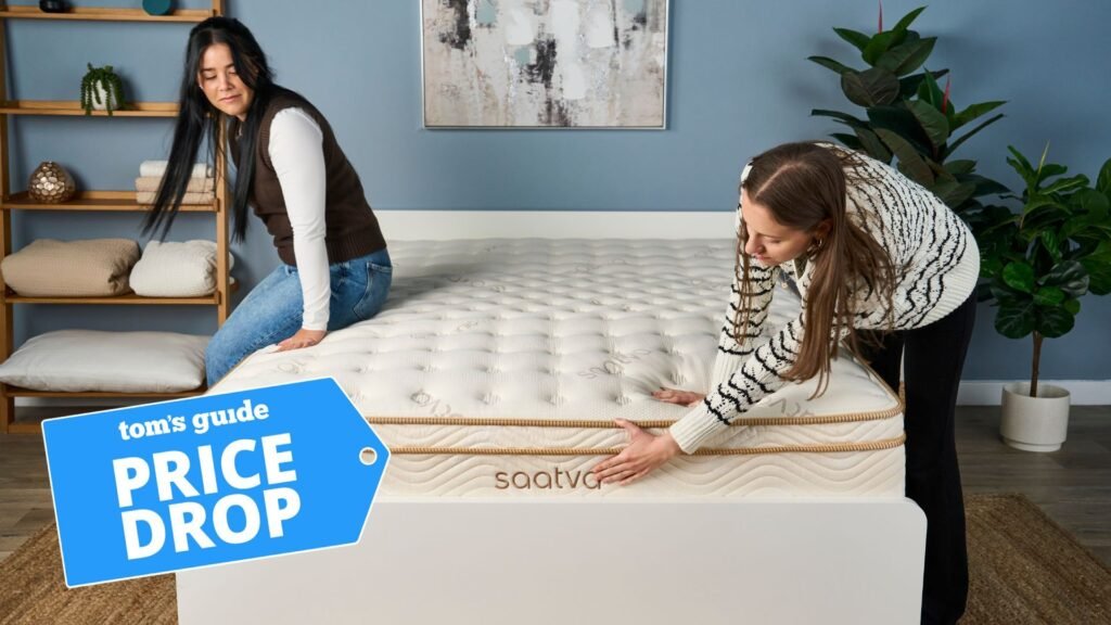 Two reviewers check out the Saatva Classic mattress. In the bottom left-hand foreground, there is a deals badge that says "PRICE DROP".