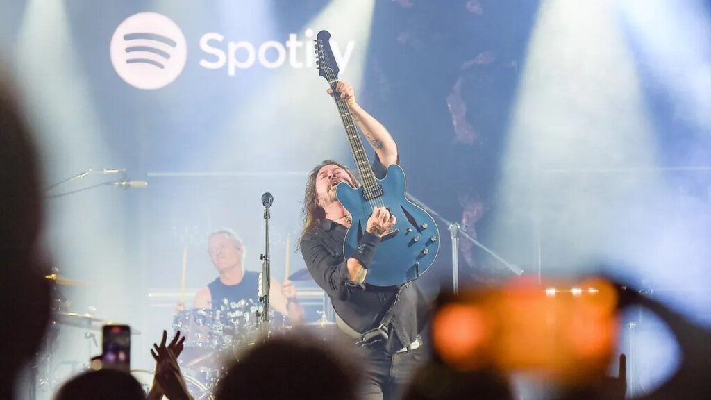 Dave Grohl holds a blue guitar in front of him as Foo Fighters play on stage.