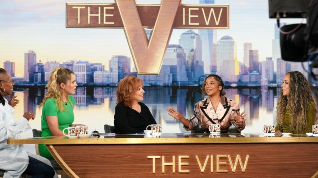 Five women sit at a table and talk during recording of an episode of The View.