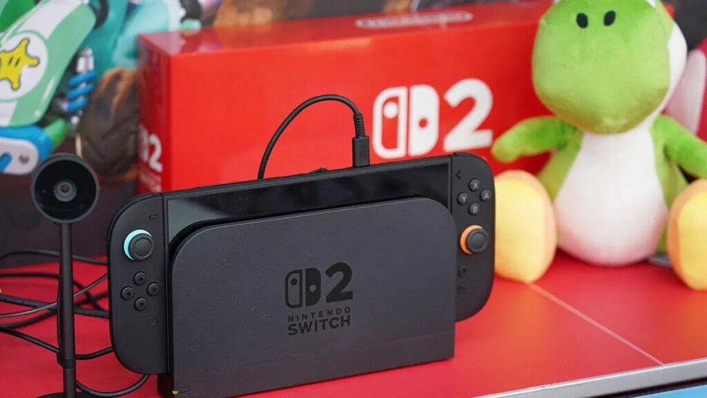 Switch 2 with Game Chat camera and charging cable sits on Nintendo display.