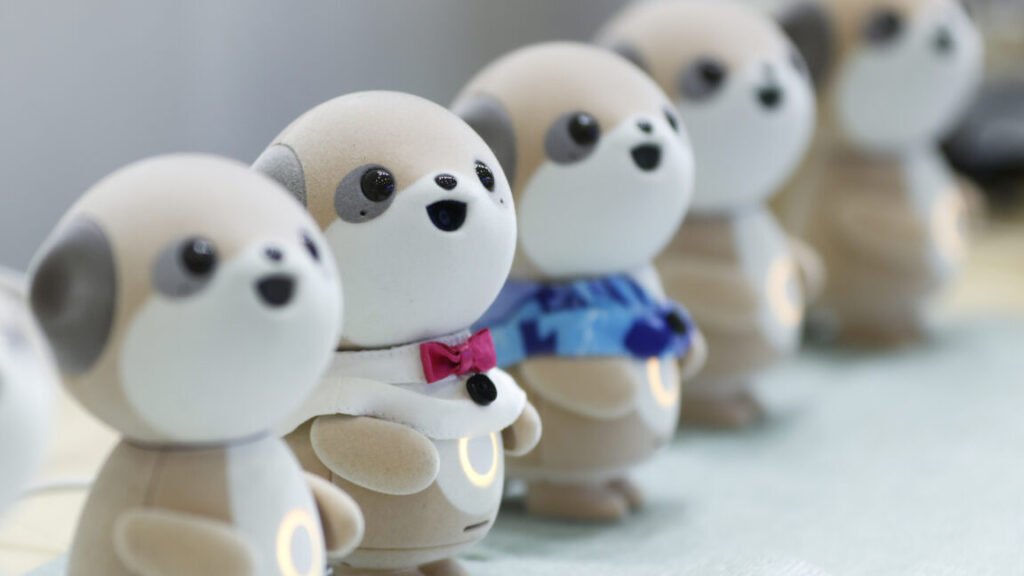 Four plastic anthropomorphic toy dogs are lined up on display at a trade show.